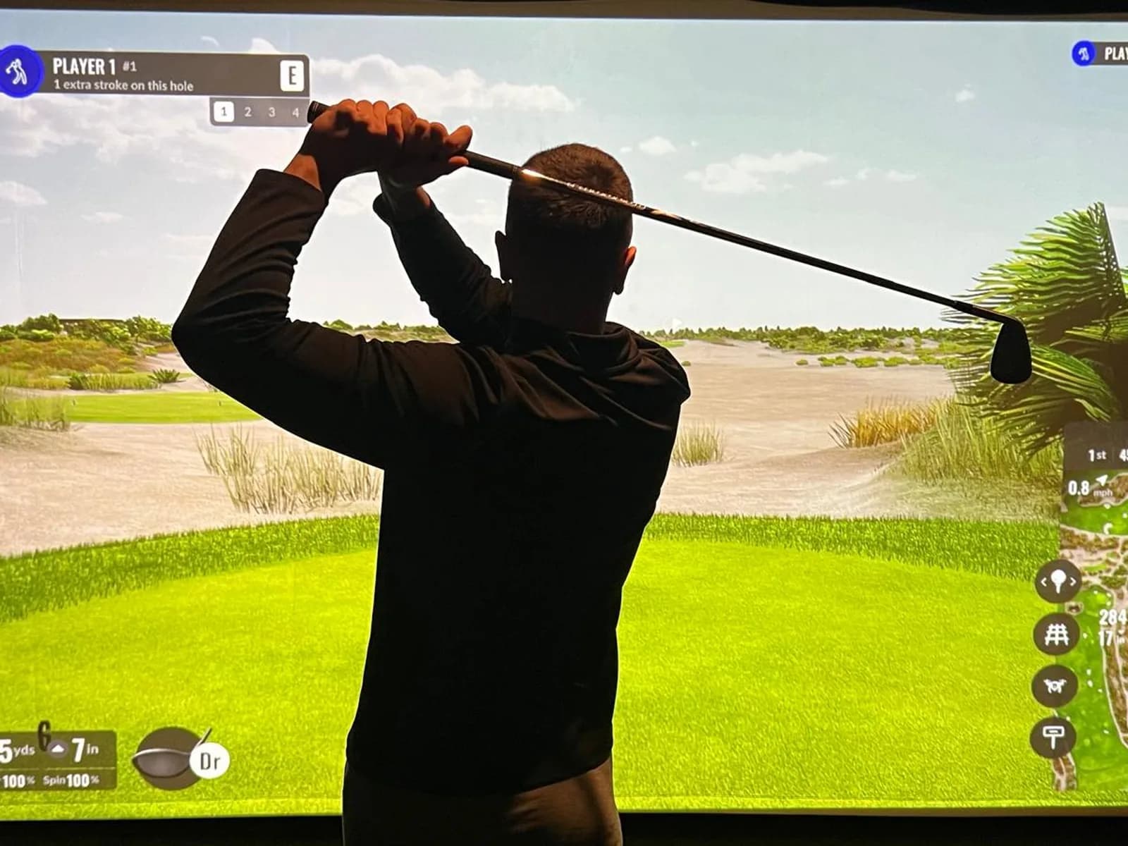 Golfer mid-swing in an enclosed Trackman simulator bay at Fliers Indoor Golf, Liverpool