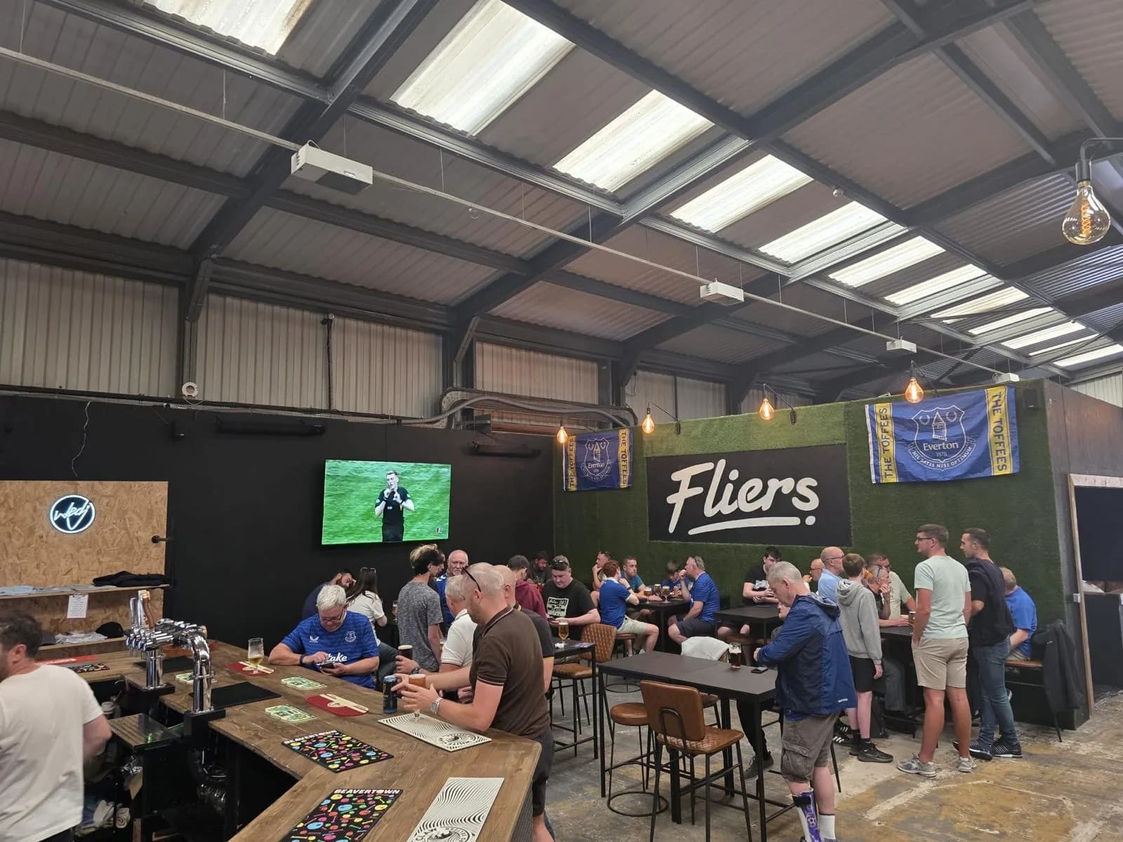 Busy bar with guests watching sport under the Fliers sign in Liverpool